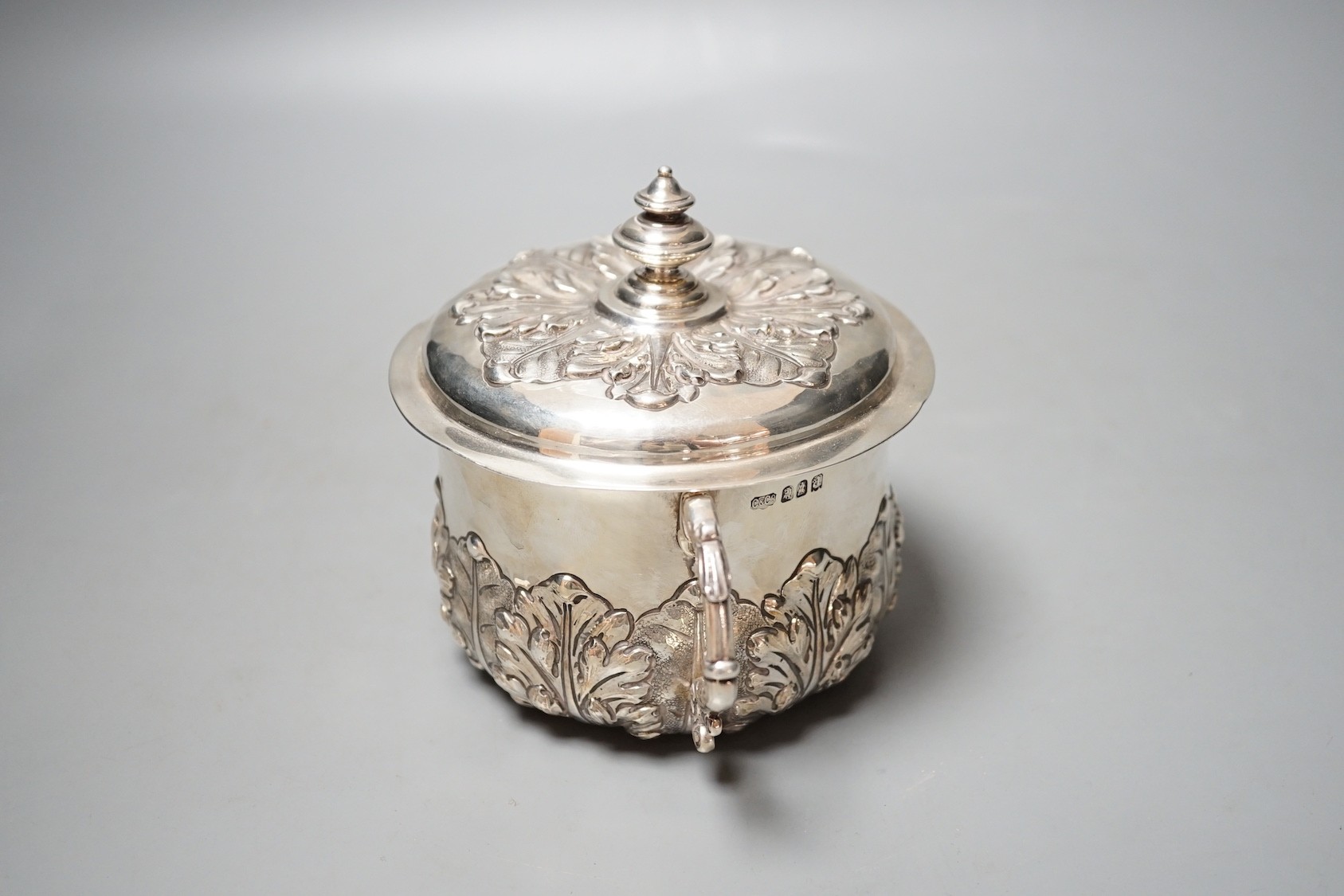 A George V embossed Brittania standard silver two handled presentation bowl and cover, Carrington & Co, London, 1916, diameter 18.6cm over handles, 18.5oz.